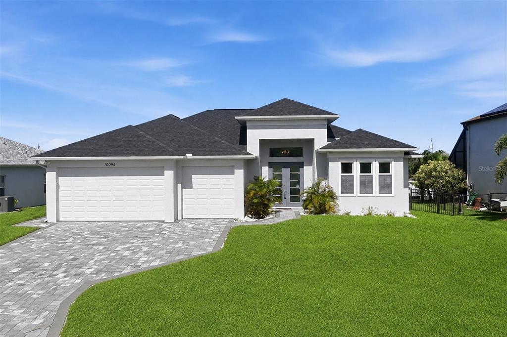 A single-story house with a gray exterior, a three-car garage, and a paved driveway — 10099 LONG BRANCH STREET, PORT CHARLOTTE, FL