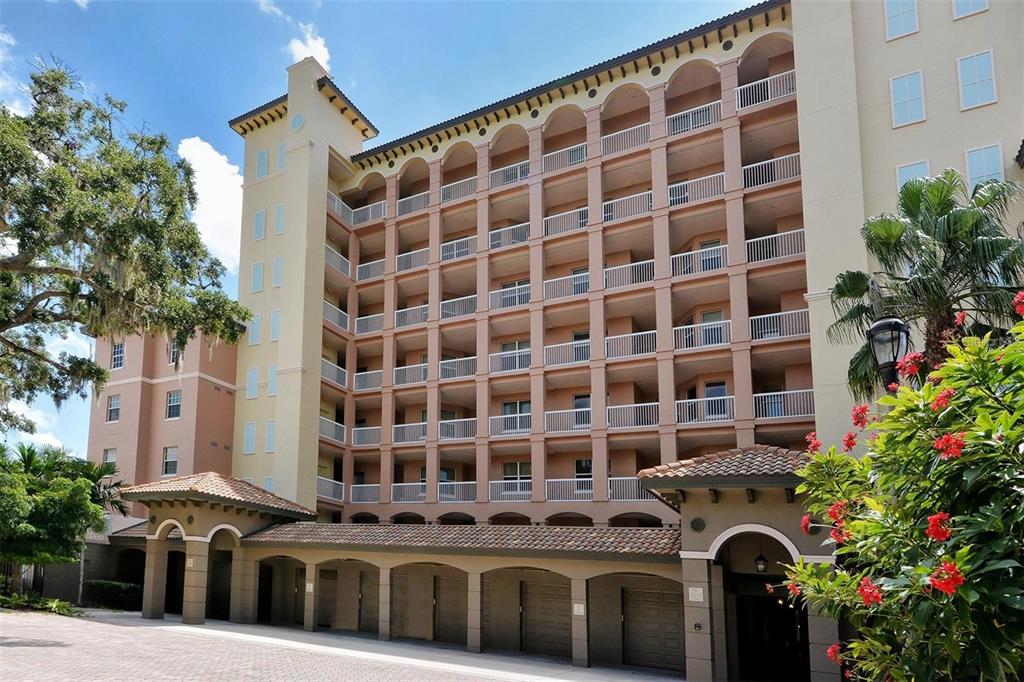 A multi-story apartment building features arched balconies and a covered ground-level parking area — 1921 MONTE CARLO DRIVE UNIT 302, SARASOTA, FL