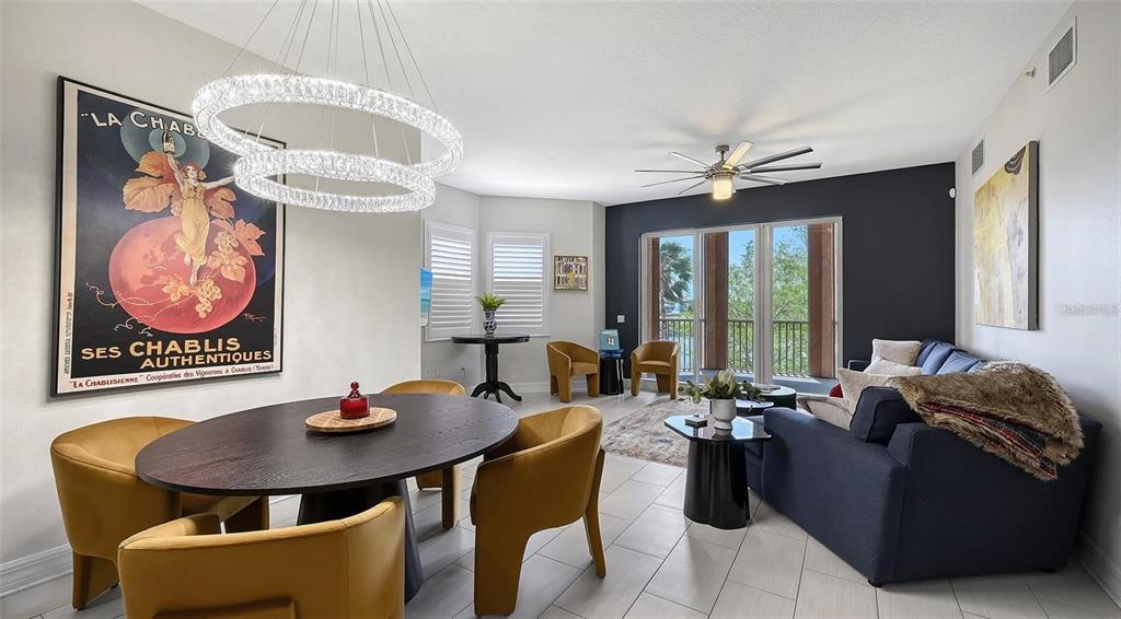 A dining and living area features a dark round table, yellow chairs, and blue sofa — 1921 MONTE CARLO DRIVE UNIT 302, SARASOTA, FL