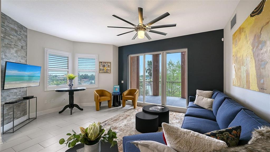 A living room features a blue sofa, two yellow chairs, and a balcony view — 1921 MONTE CARLO DRIVE UNIT 302, SARASOTA, FL