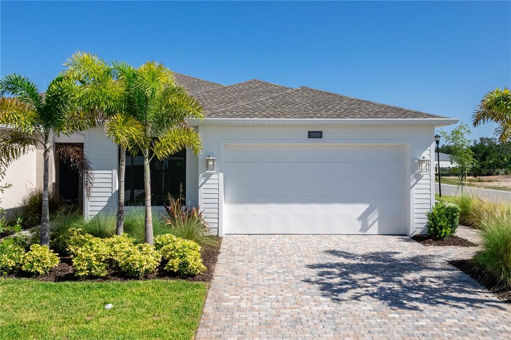 A white single-story house features a two-car garage, palm trees, and a paved driveway — 5890 WINDBREAK COURT, APOLLO BEACH, FL