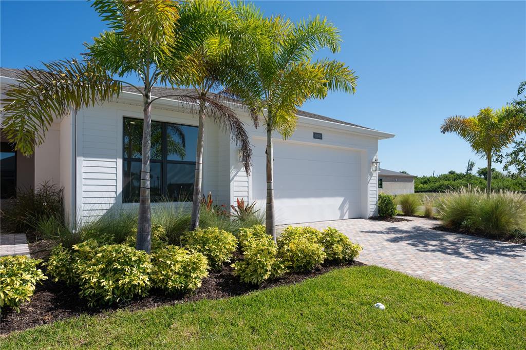 A white house exterior features a two-car garage, palm trees, and a paved driveway — 5890 WINDBREAK COURT, APOLLO BEACH, FL