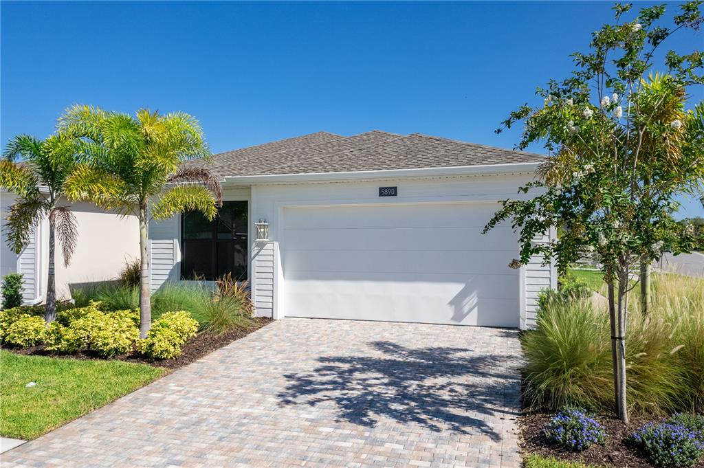A single-story house exterior features a white garage, a paved driveway, and palm trees — 5890 WINDBREAK COURT, APOLLO BEACH, FL