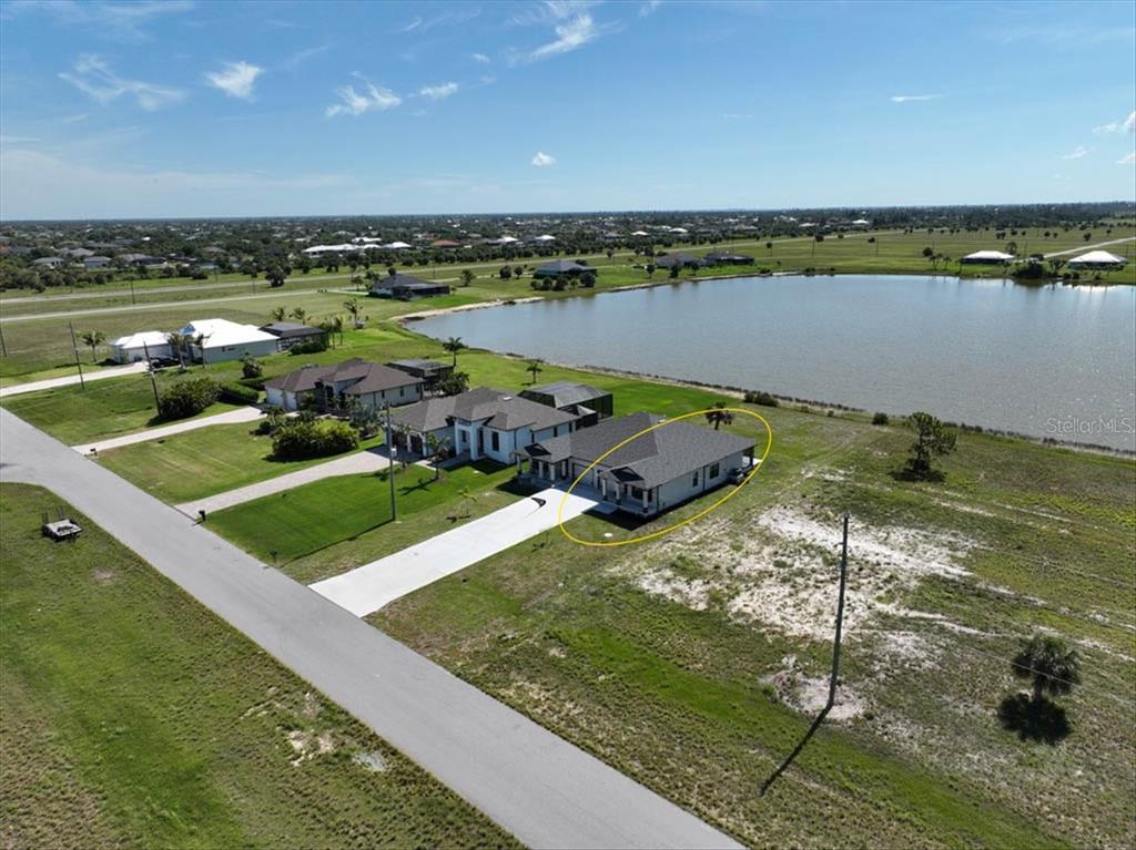An aerial view shows a single-story house with a dark roof next to a lake — 44 YELLOWHAMMER DRIVE, PLACIDA, FL