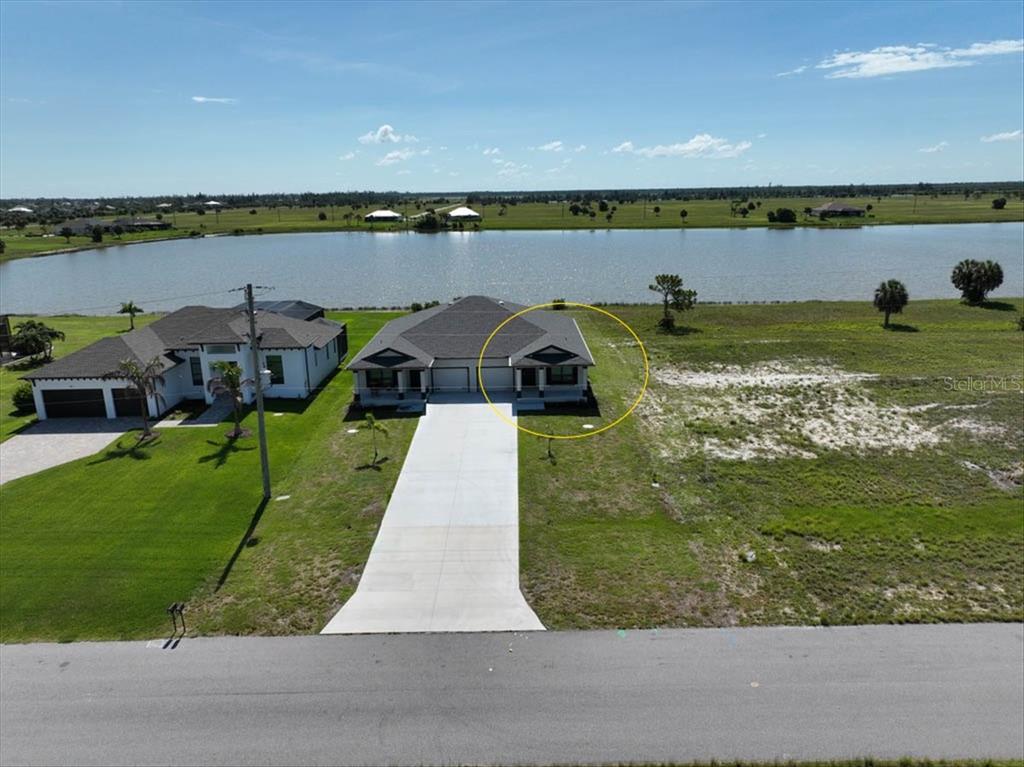 An aerial view shows a duplex house with a concrete driveway next to a lake — 44 YELLOWHAMMER DRIVE, PLACIDA, FL