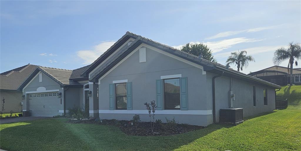A single-story gray house with a two-car garage, blue shutters, and a tiled roof — 4222 JULIANA LAKE DRIVE, AUBURNDALE, FL