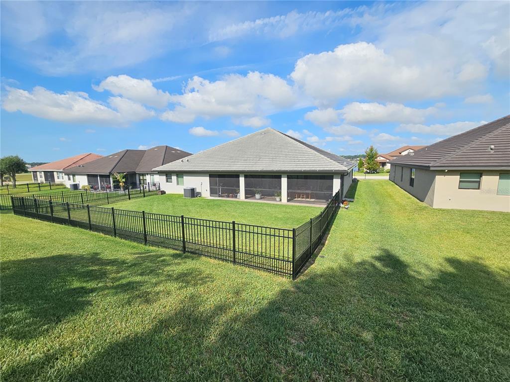 A fenced backyard with a screened patio attached to a single-story house — 4222 JULIANA LAKE DRIVE, AUBURNDALE, FL