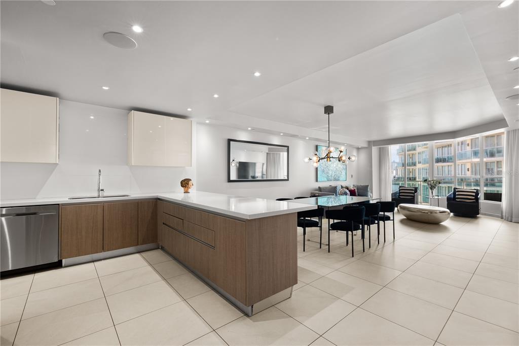 A modern kitchen with wood cabinets and white countertops opens into a dining and living area — 25 MUNOZ RIVERA UNIT 704, SAN JUAN, PR