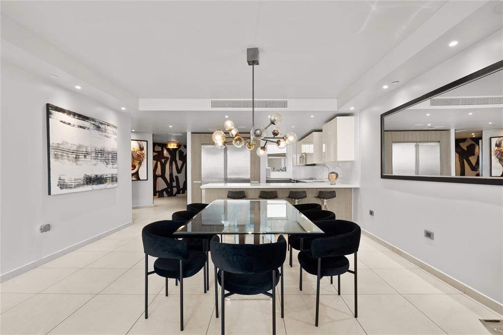 A dining area features a glass table, black chairs, and a modern chandelier near a kitchen — 25 MUNOZ RIVERA UNIT 704, SAN JUAN, PR