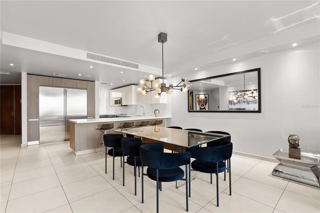 A modern dining area features a glass table, dark velvet chairs, and a contemporary chandelier — 25 MUNOZ RIVERA UNIT 704, SAN JUAN, PR
