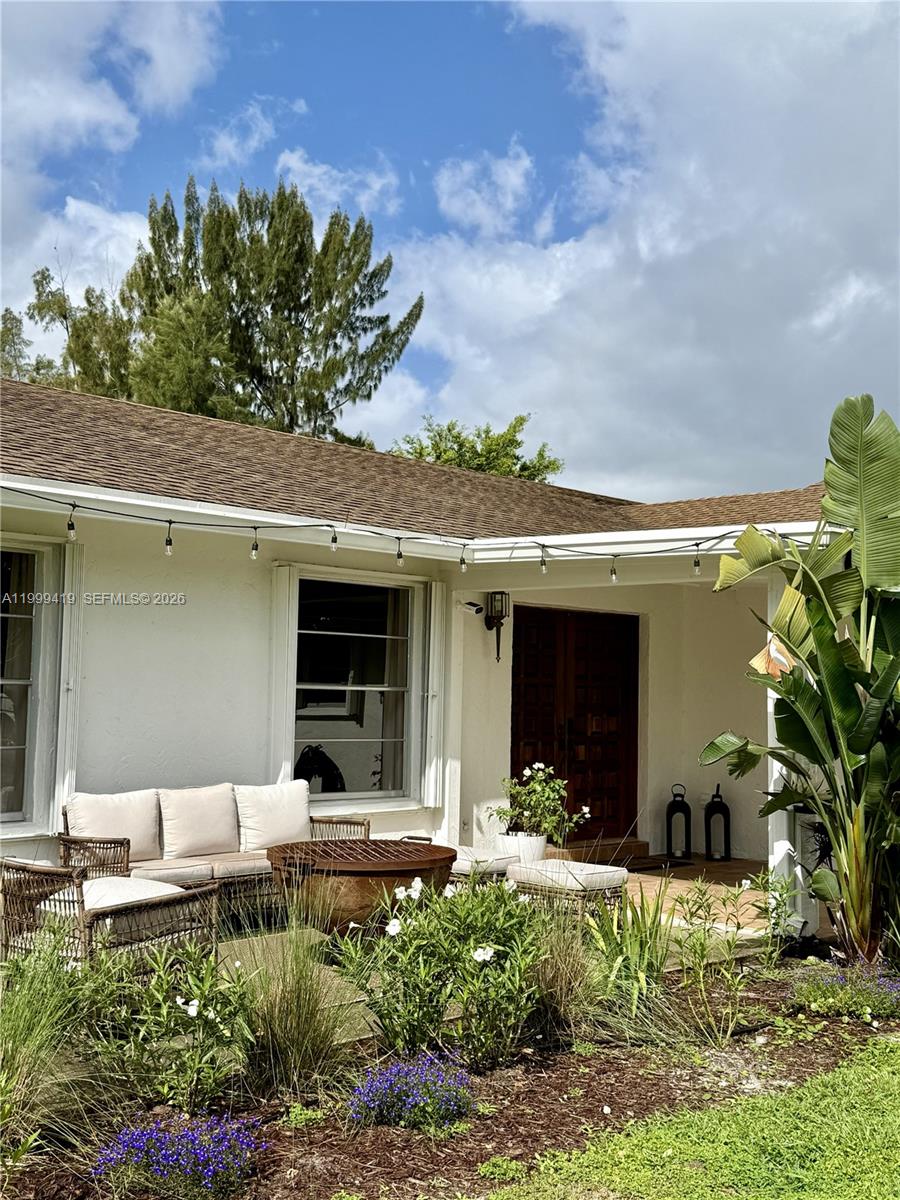 A patio features outdoor furniture, a fire pit, and string lights in front of a house — 625 Whippoorwill Ter, West Palm Beach FL 33411, WEST PALM BEACH, FL