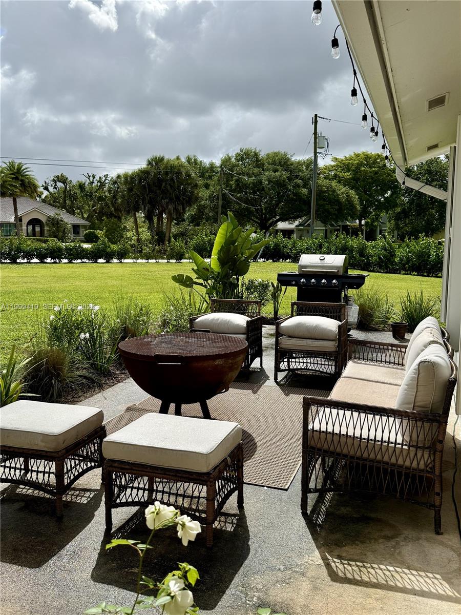 A patio features wicker furniture, a fire pit, and a grill overlooking a grassy yard — 625 Whippoorwill Ter, West Palm Beach FL 33411, WEST PALM BEACH, FL