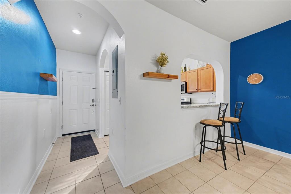 An entryway leads to a kitchen pass-through window with two bar stools and blue walls — 3505 45TH TERRACE W UNIT 105, BRADENTON, FL