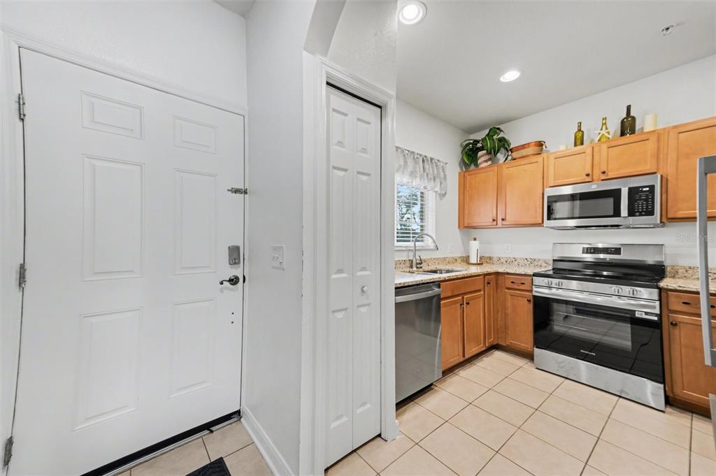 A kitchen features light wood cabinets, stainless steel appliances, and beige tile flooring — 3505 45TH TERRACE W UNIT 105, BRADENTON, FL