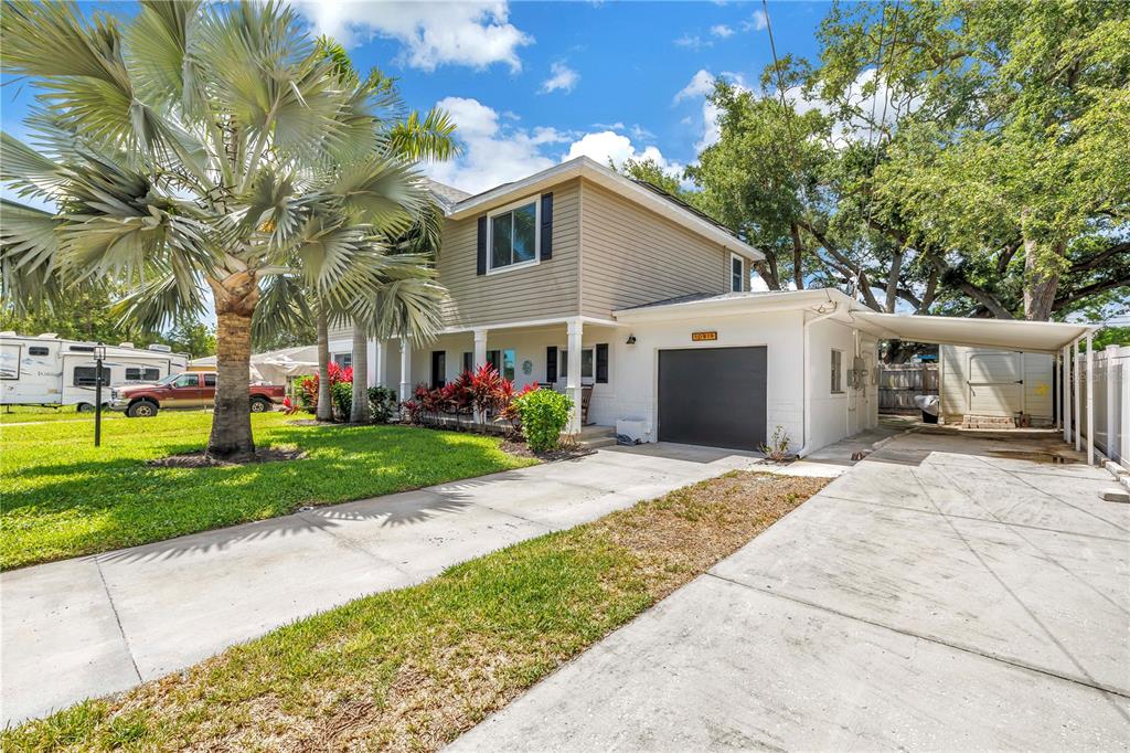 A two-story house with tan siding, a white brick lower level, and a concrete driveway — 10819 SEMINOLE DRIVE N, ST PETERSBURG, FL