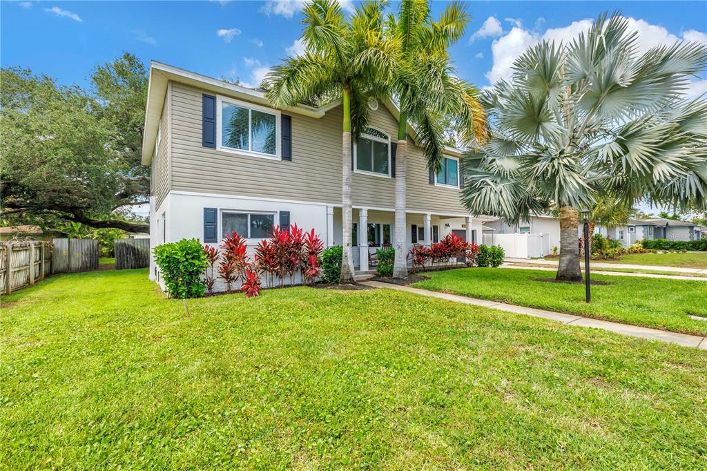 A two-story house with beige siding, a white lower level, and palm trees in the yard — 10819 SEMINOLE DRIVE N, ST PETERSBURG, FL