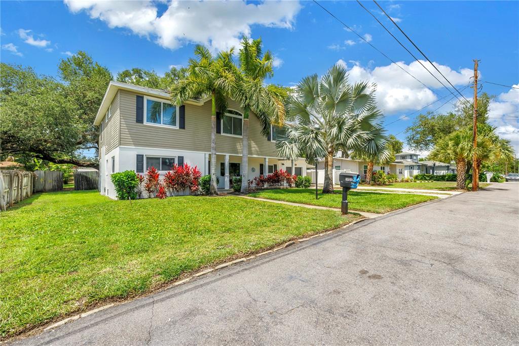 A two-story house with tan siding, palm trees, and a front lawn on a street — 10819 SEMINOLE DRIVE N, ST PETERSBURG, FL