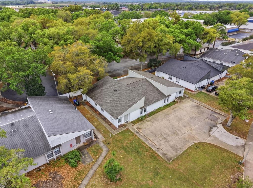 An aerial view shows three single-story buildings with gray roofs surrounded by trees and pavement — 1912-1918 CRYSTAL GROVE DRIVE, LAKELAND, FL