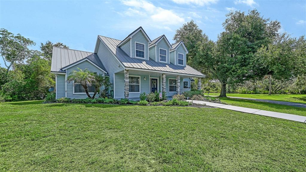 A two-story house with light blue siding, a metal roof, and stone-accented porch columns — 28401 104TH DR E, MYAKKA CITY, FL