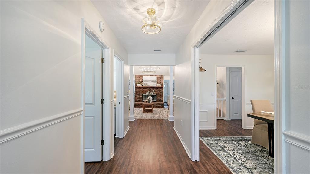 A hallway with wood-look flooring leads to a living room with a brick fireplace — 28401 104TH DR E, MYAKKA CITY, FL