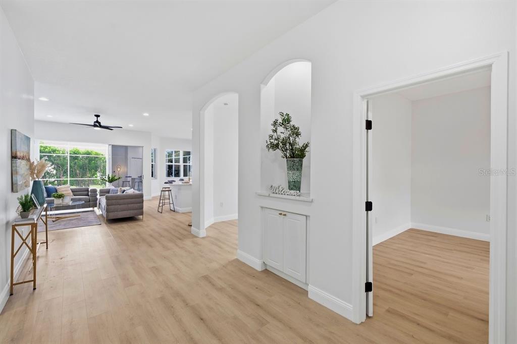 A bright hallway leads to an open living area with light wood floors and arched niches — 6011 CHAPARRAL AVENUE, SARASOTA, FL
