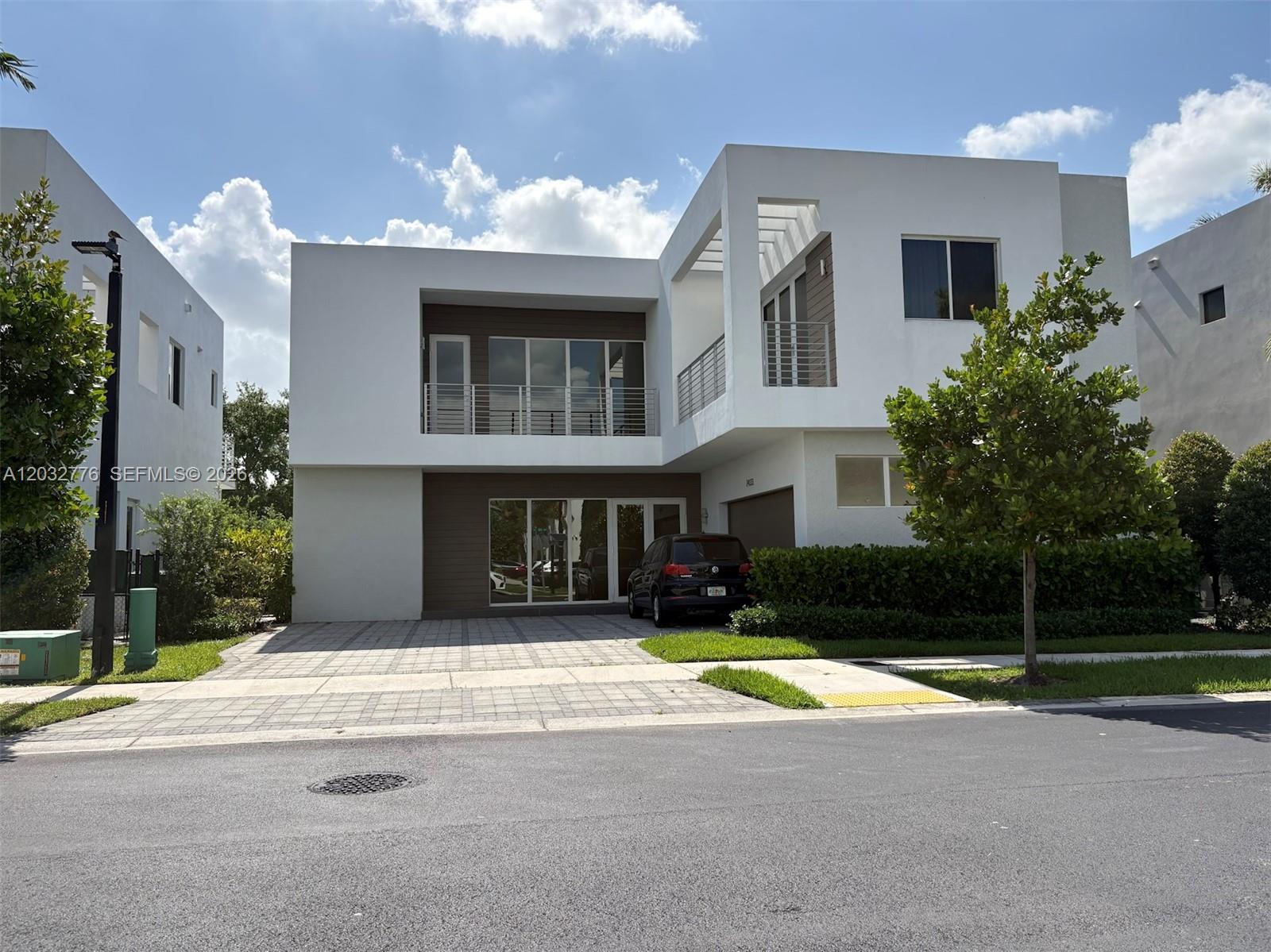 A two-story modern house with white stucco, wood-paneled accents, and a paved driveway — 7433 NW 99th Ave, Doral FL 33178, DORAL, FL