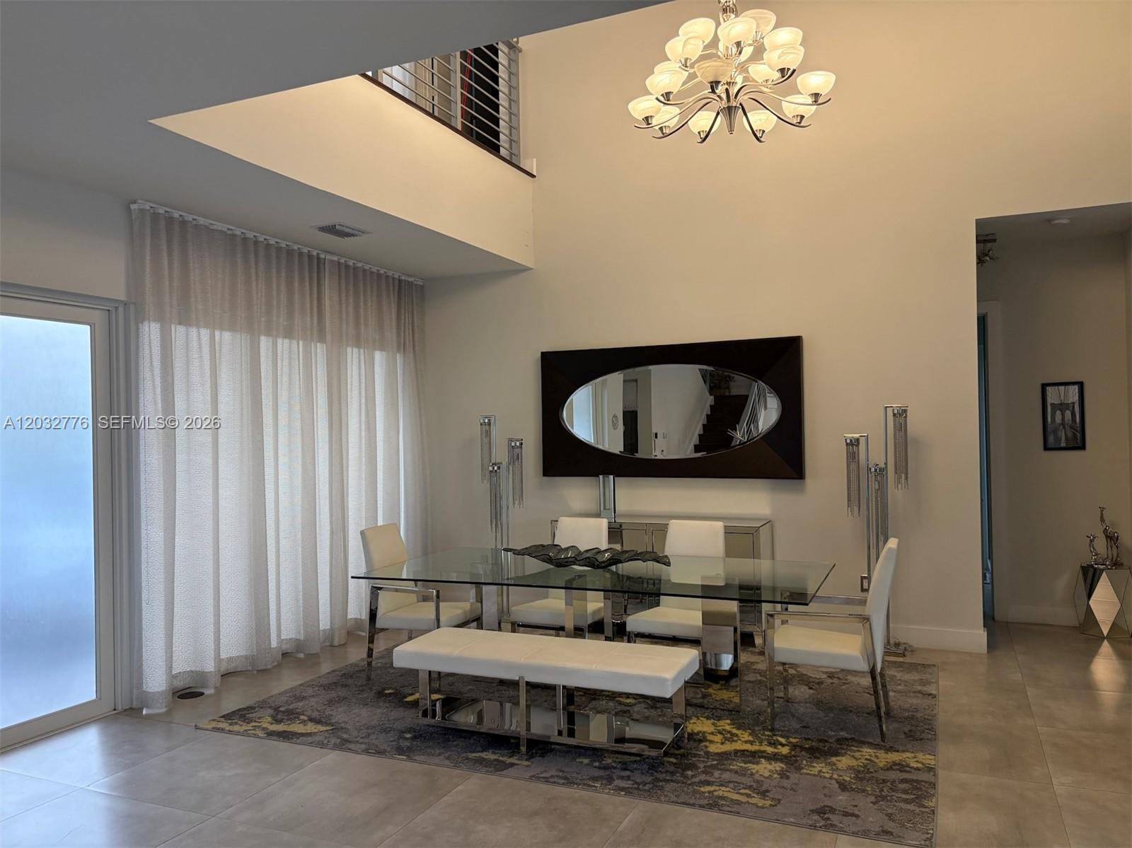 A modern dining room features a glass table, white chairs, and a large oval mirror — 7433 NW 99th Ave, Doral FL 33178, DORAL, FL