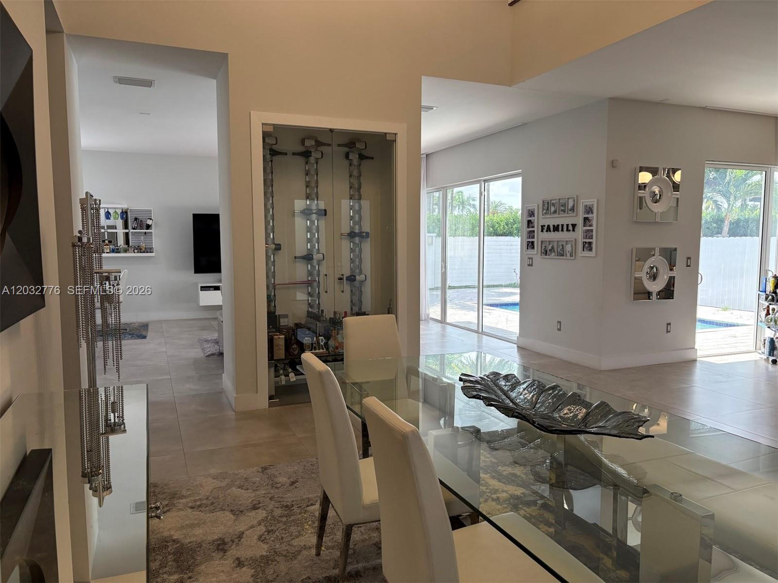 A dining area features a glass table, white chairs, and a built-in glass wine display — 7433 NW 99th Ave, Doral FL 33178, DORAL, FL