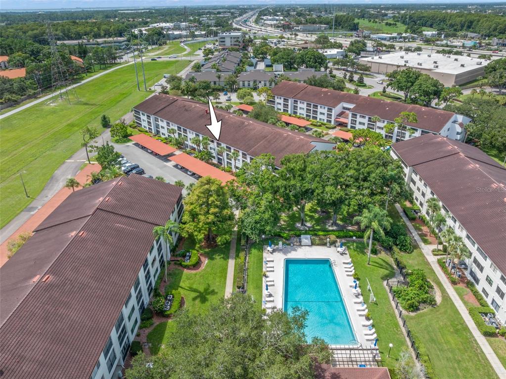 An aerial view shows multi-story apartment buildings, a swimming pool, and parking areas — 2593 COUNTRYSIDE BOULEVARD UNIT 7304, CLEARWATER, FL