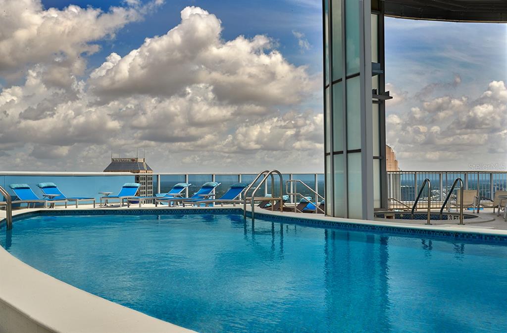 A rooftop swimming pool with lounge chairs overlooks a city skyline under a cloudy sky — 111-4 WASHINGTON STREET, ORLANDO, FL