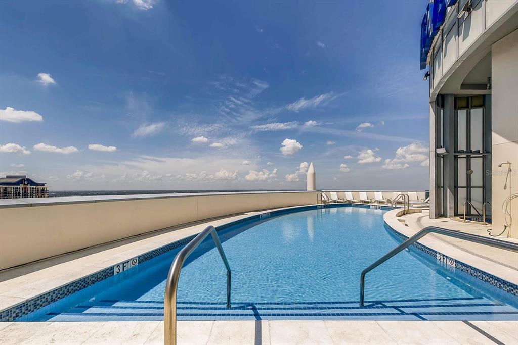 An outdoor rooftop swimming pool with a metal railing overlooks a distant horizon — 111-4 WASHINGTON STREET, ORLANDO, FL