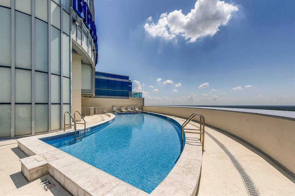 An outdoor rooftop swimming pool with a curved edge overlooks a distant horizon — 111-4 WASHINGTON STREET, ORLANDO, FL