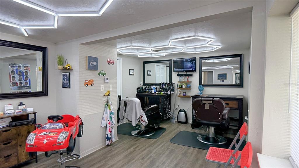 A barbershop features two styling stations, a red car-shaped child's chair, and hexagonal ceiling lights — 325 NE 25 AVENUE, OCALA, FL