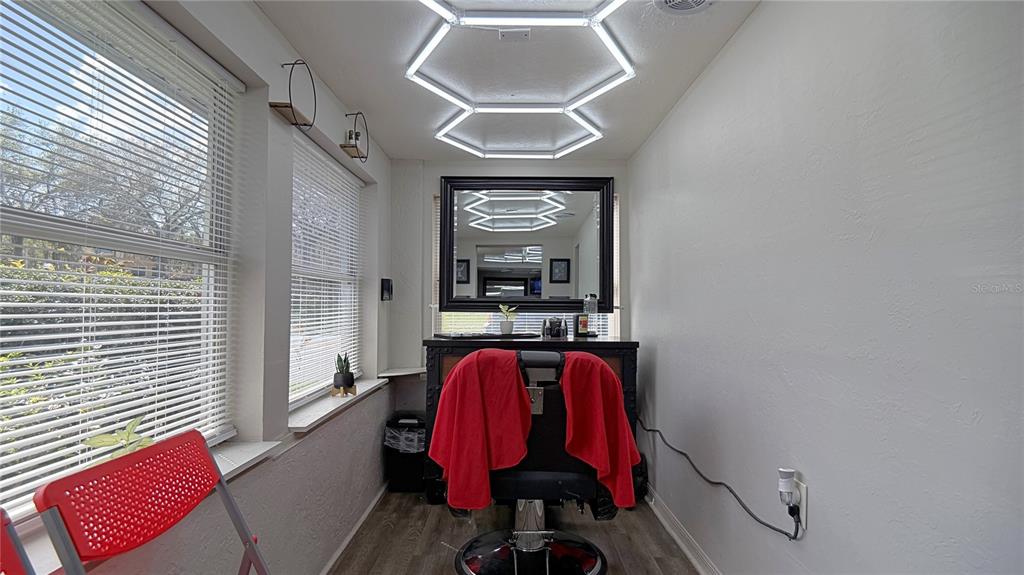 A small salon room features a barber chair, a large mirror, and geometric ceiling lights — 325 NE 25 AVENUE, OCALA, FL