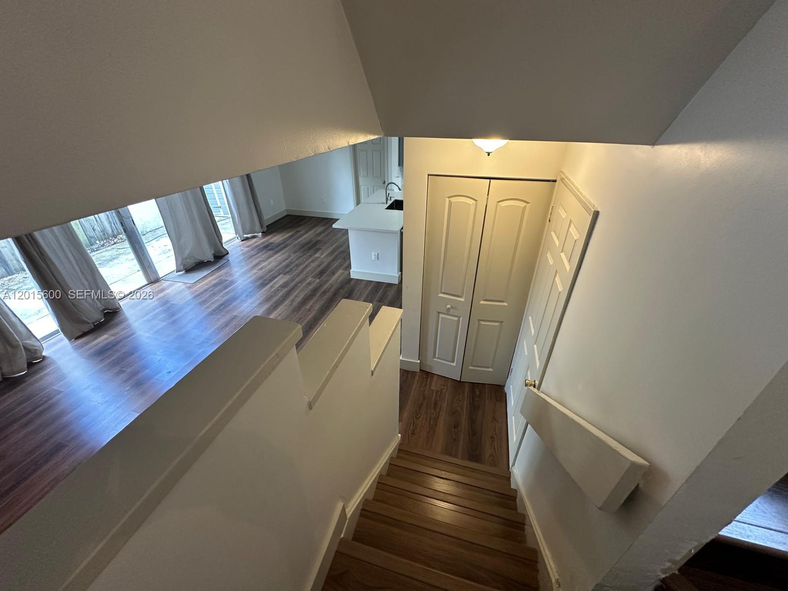 A view looking down a wooden staircase toward a living area with wood-look flooring — 9062 SW 147th Ct, Miami FL 33196, MIAMI, FL