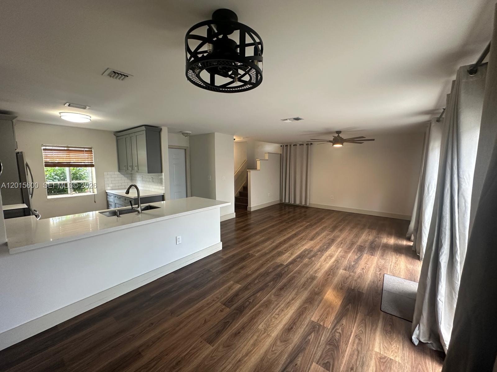 An open-concept kitchen and living area features wood-look flooring, gray cabinets, and a ceiling fan — 9062 SW 147th Ct, Miami FL 33196, MIAMI, FL