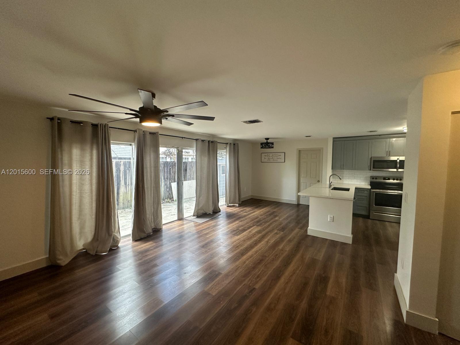 An open-concept living area features wood-look flooring, a ceiling fan, and an adjacent kitchen — 9062 SW 147th Ct, Miami FL 33196, MIAMI, FL