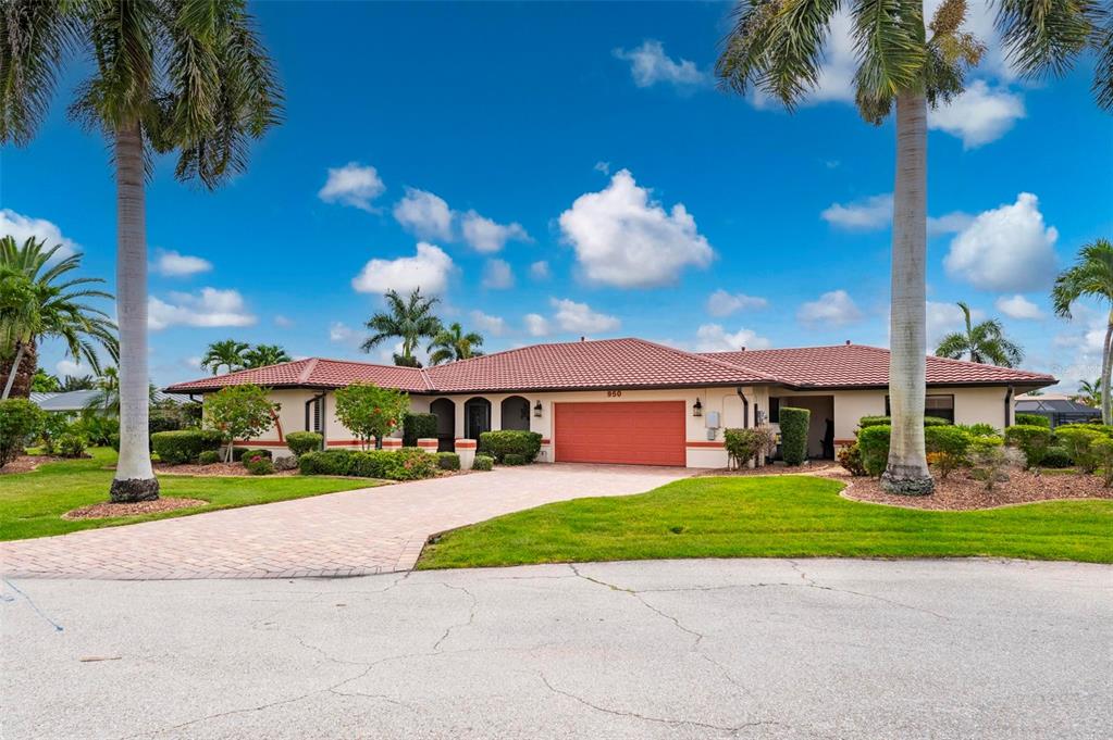 A single-story house with a red tile roof, orange garage door, and paved driveway — 950 LASSINO COURT, PUNTA GORDA, FL