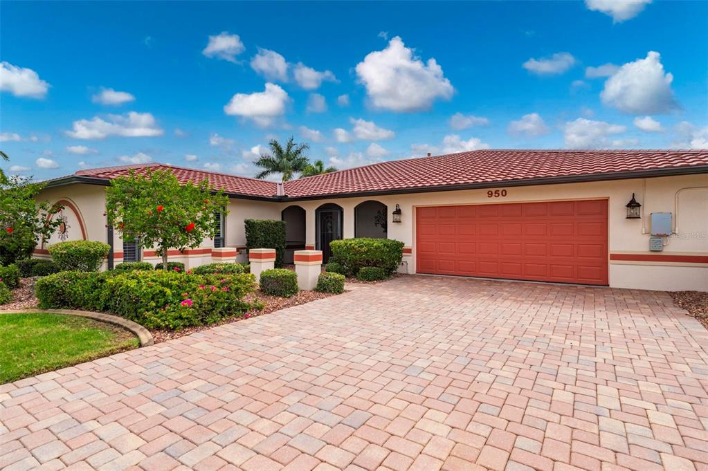 A single-story house exterior features a red tile roof, orange accents, and a paved walkway — 950 LASSINO COURT, PUNTA GORDA, FL
