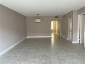 A spacious living room features light-colored tile flooring, neutral wall paint, and a hanging light fixture — 158 Lakeview Drive, Weston FL 33326, WESTON, FL