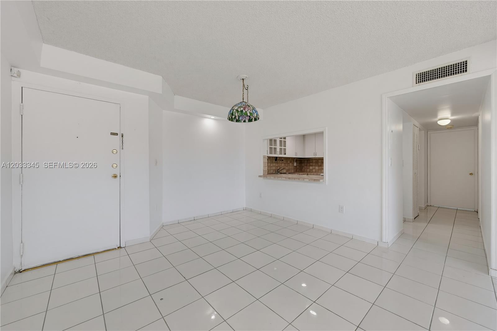 A tiled dining area features a stained-glass pendant light and a pass-through to the kitchen — 8050 NW 8th St # 110, Miami FL 33126, MIAMI, FL