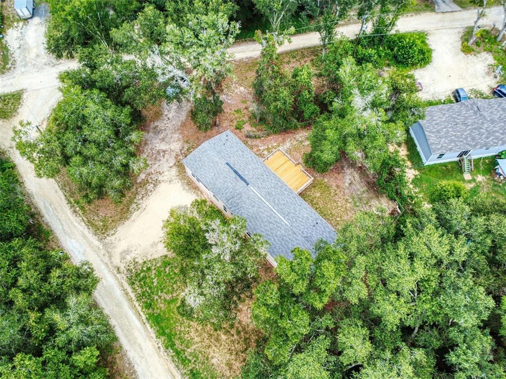 An aerial view shows a rectangular house with a wooden deck surrounded by dense trees — 12841 SE 103RD TERRACE, BELLEVIEW, FL