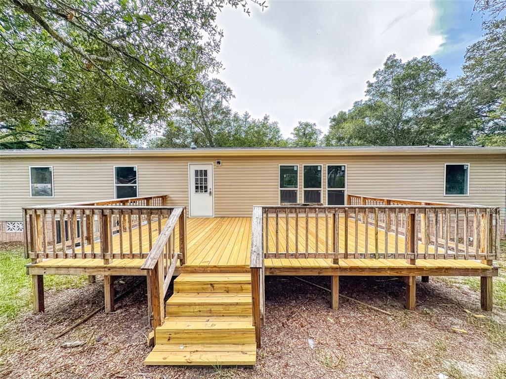 A light-colored mobile home features a large, newly built wooden deck with stairs — 12841 SE 103RD TERRACE, BELLEVIEW, FL
