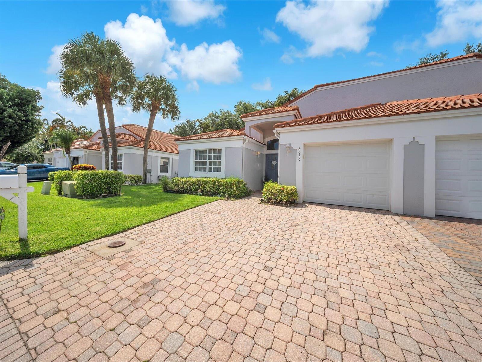 A single-story house with a paved driveway, white garage doors, and a red tile roof — 8039 N Tranquility Lake Drive, Delray Beach FL 33446, DELRAY BEACH, FL