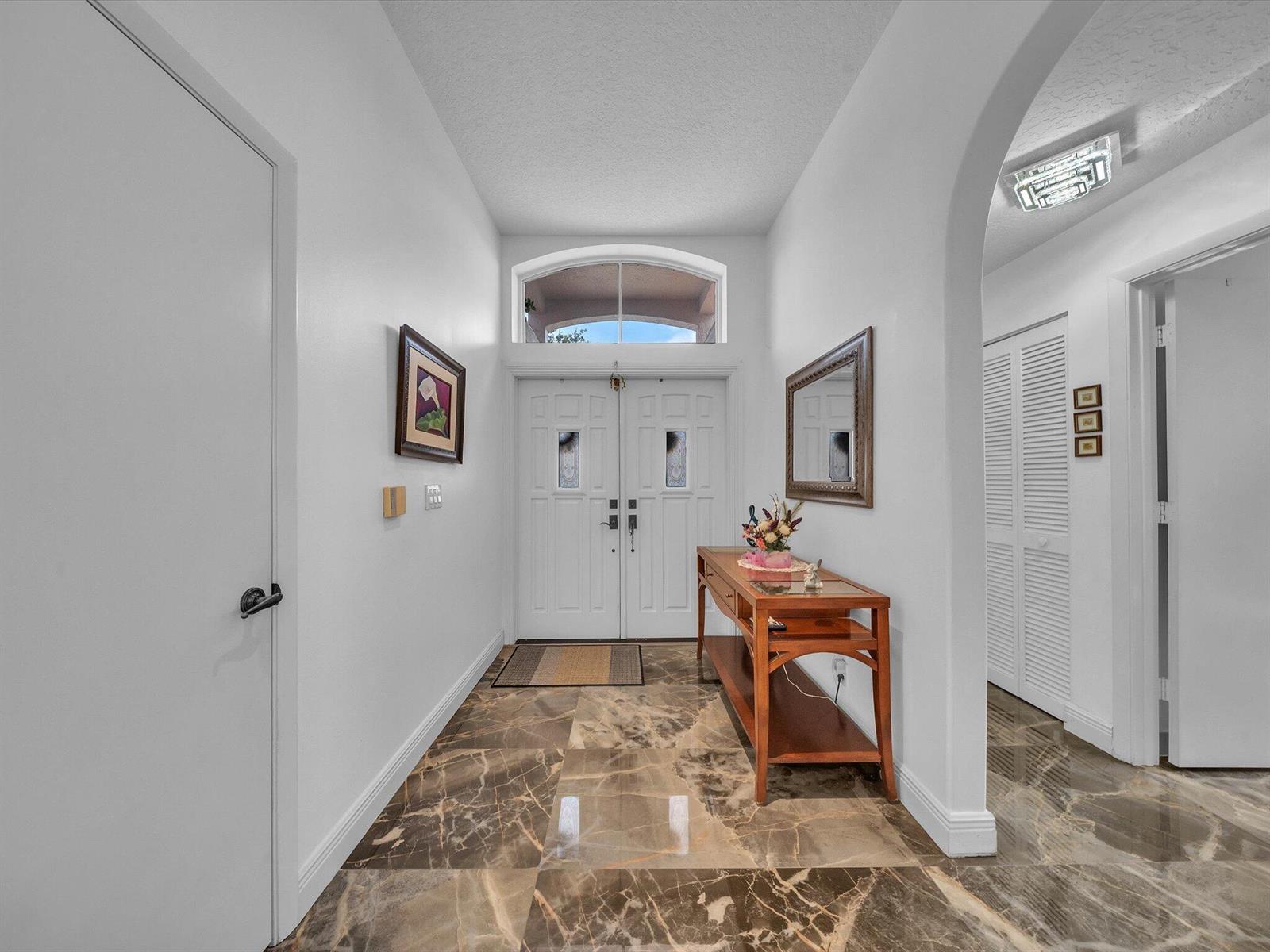 A foyer features marble-look tile flooring, a wooden console table, and double front entry doors — 8039 N Tranquility Lake Drive, Delray Beach FL 33446, DELRAY BEACH, FL
