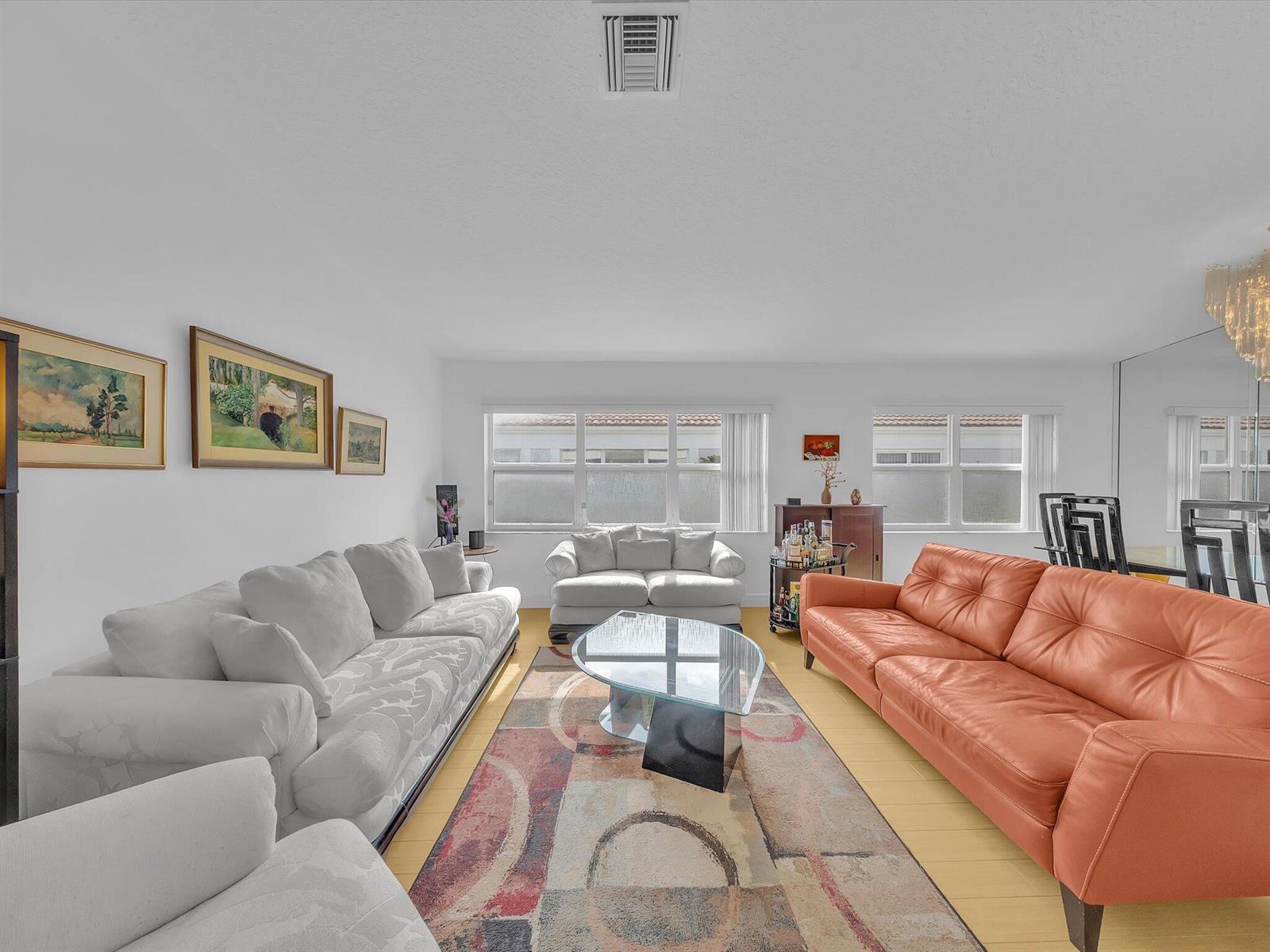 A living room features a white sofa, an orange leather sofa, and a glass coffee table — 8039 N Tranquility Lake Drive, Delray Beach FL 33446, DELRAY BEACH, FL