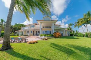A large two-story house with a lawn, palm trees, and lounge chairs on the patio — 901 SE Riverside Drive, Stuart FL 34994, STUART, FL