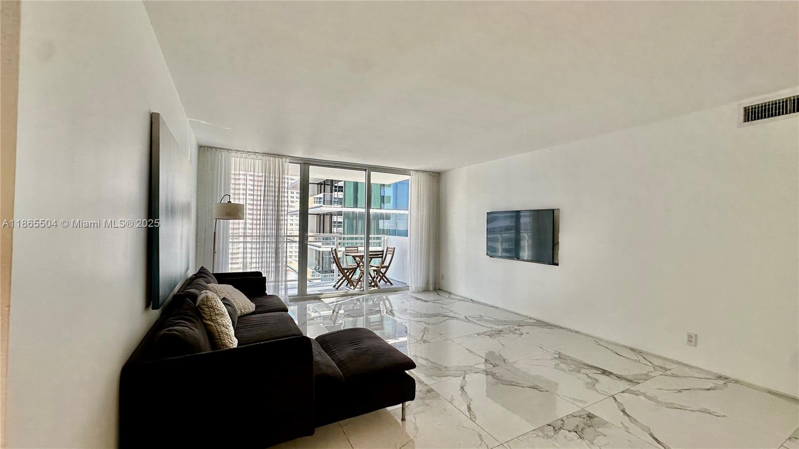 A living room features white marble floors, a dark sofa, and a balcony with outdoor seating — 2030 S Ocean Dr # 1022, Hallandale Beach FL 33009, HALLANDALE BEACH, FL