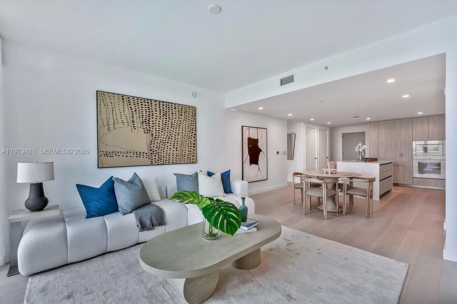A modern living room features a white sofa, oval coffee table, and adjacent dining area — 9201 E Bay Harbor Dr # 503, Bal Harbour FL 33154, BAL HARBOUR, FL