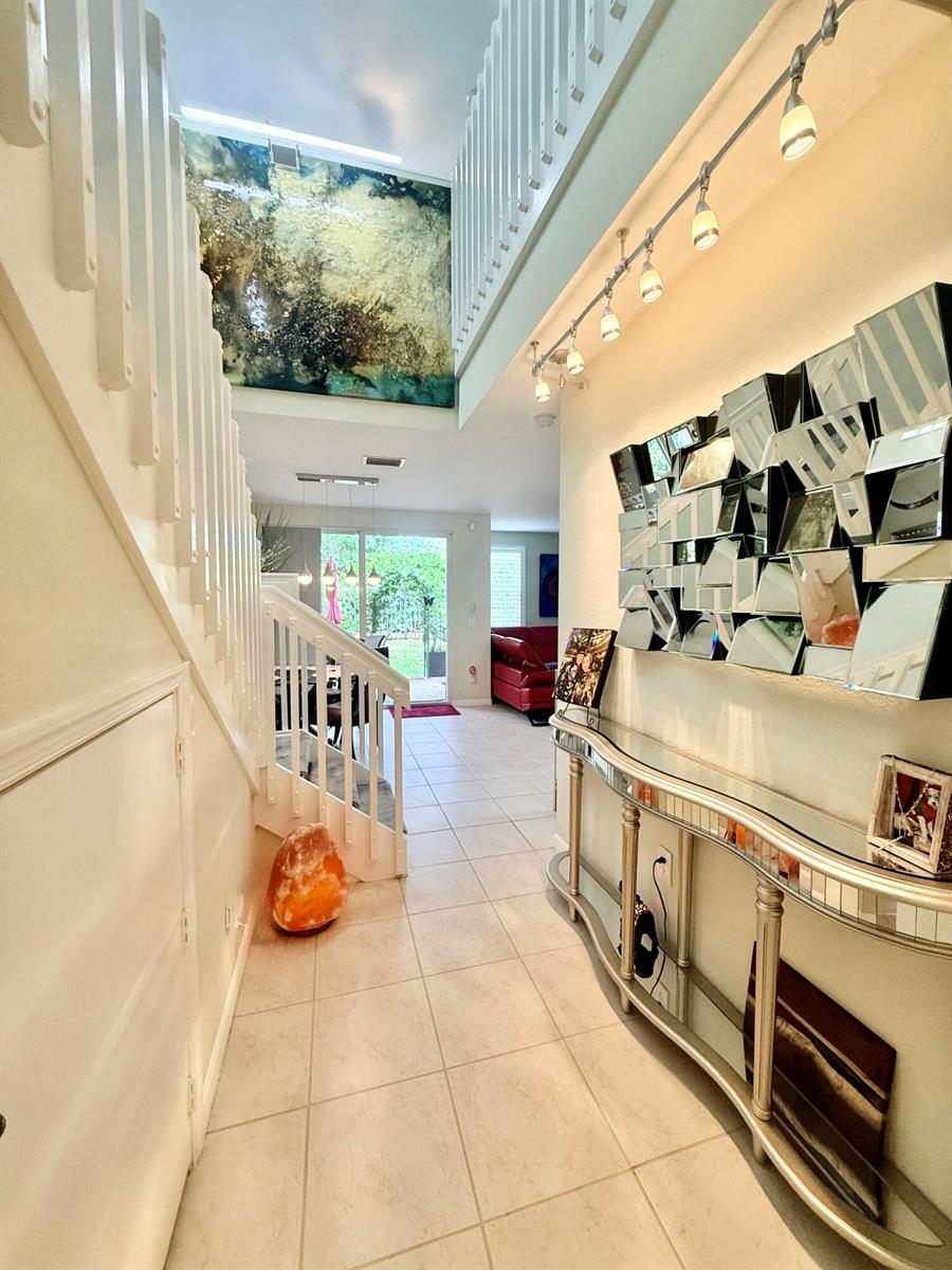 A tiled entryway features a mirrored console table, a wall of mirrors, and a staircase — 1015 Ventnor Avenue # 3a, Delray Beach FL 33444, DELRAY BEACH, FL